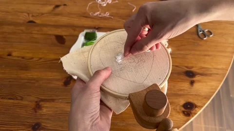Female hands doing hand embroidery stitching process on wooden table Stock Footage 335193841