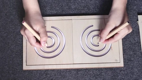 Female hands drawing lines in two-sided wooden stencil labyrinth Stock Footage 157671682