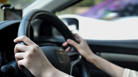 Female hands of the driver on the steering wheel while driving a car on asphalt Stock Footage 336267050