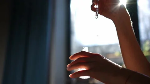 Female hands dropping perfume drops on palm skin in sunbeam indoors Video stock 221863541