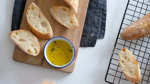 Female hands dunk bread in olive oil, which flows onto a slice of bread. Healthy Stock Footage 121527701