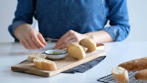 Female hands dunk bread in olive oil, which flows onto a slice of bread. Healthy Stock Footage 128255750