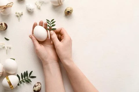 Female hands with Easter eggs, leaves and beautiful gypsophila flowers on whi Stock Photos