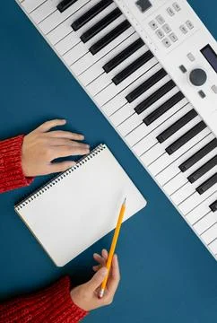 Female hands, empty notepad and music keys on green background, flat lay. Foto stock