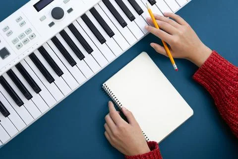Female hands, empty notepad and music keys on green background, flat lay. Foto stock