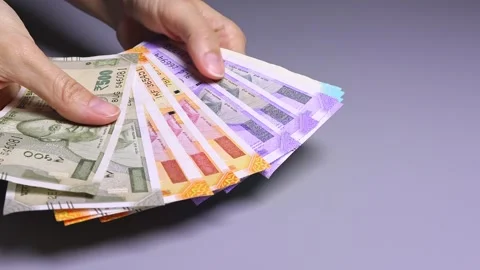 Female hands fanning out a stack of Indian bills on a background of a gray table Stock Footage 303508606