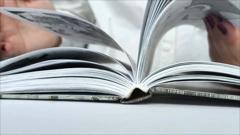 Female hands flip through the pages of a book on the table. Stock Footage 311993738