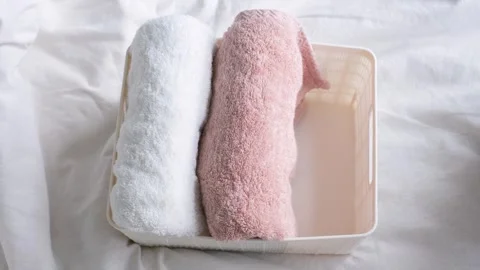 Female hands folding towels in plastic box on the background of a white Stock Footage 265193502