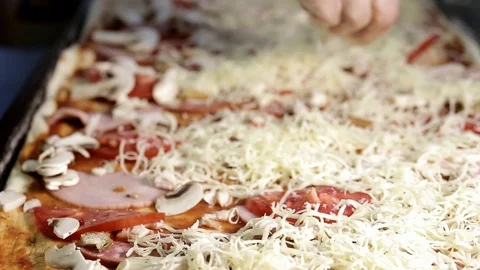 Female hands in gloves fall asleep with grated cheese a large rectangular pizza Stock Footage 101201683