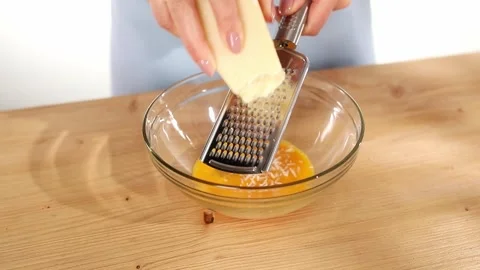 Female hands grate cheese over a bowl of eggs. cooking pasta carbonara. Stock Footage 245346341