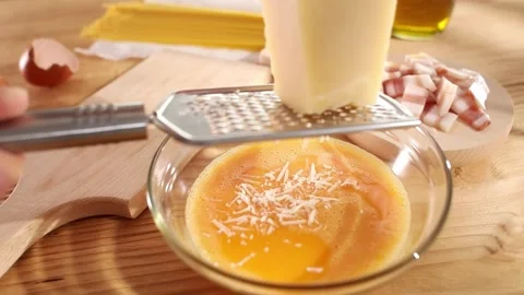 Female hands grate cheese over a bowl of eggs. cooking pasta carbonara. Stock Footage 245355359