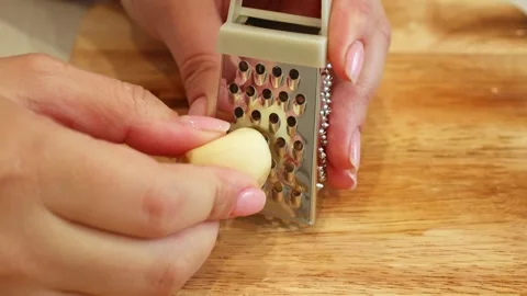 Female hands grating garlic with a small metal grater close up Stock Footage 283089637