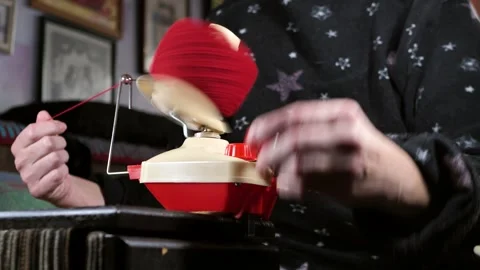 Female hands on a hand winding machine winding a new skein of red yarn. Woman Stock Footage 304438088