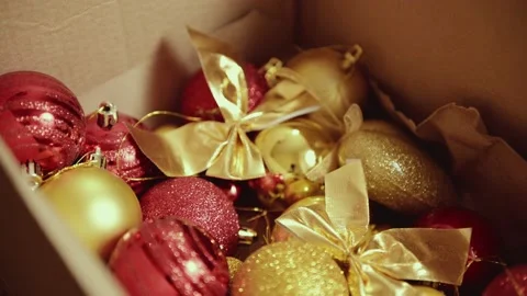 Female hands hold a cardboard box with Christmas toys, golden and red balls Stock Footage