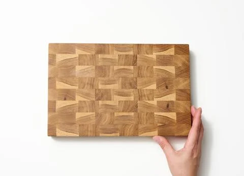 Female hands hold empty rectangular brown wooden chopping board on white back Stock Photos