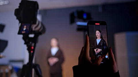 Female hands hold a phone taking video of a beautiful brunette lady.  Stock Footage 333579155