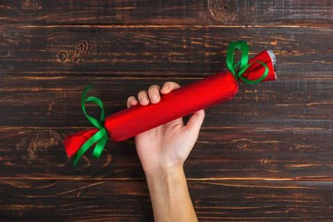 Female hands hold a red gift with a green ribbon. On the background of a wood Stock Photos