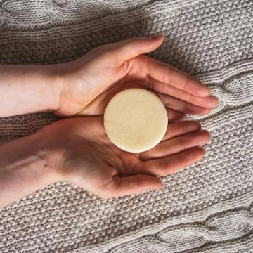 Female hands hold solid shampoo bar Stock Photos