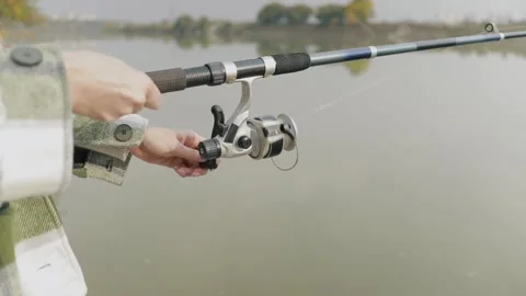 Female hands hold a spinning rod. Close-up shot of unwinding winding fishing lin Stock Footage 163253953