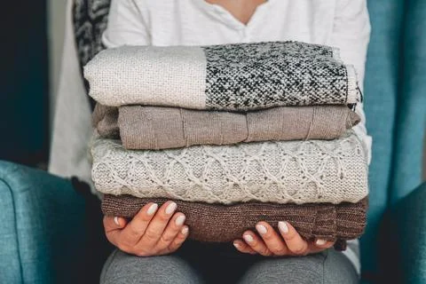Female hands hold a stack of warm knitted sweaters Stock Photos