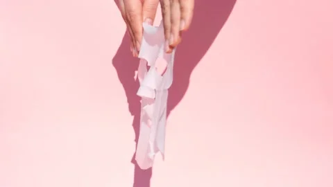 Female hands hold white sheet mask on pink background. Video stock 166841382
