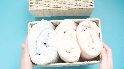 Female hands hold wicker box with rolled towels inside on a blue background top Stock Footage 201449102