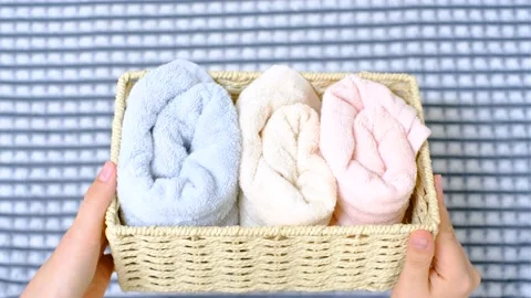 Female hands hold wicker box with rolled towels inside on a gray background top Stock Footage 201502889