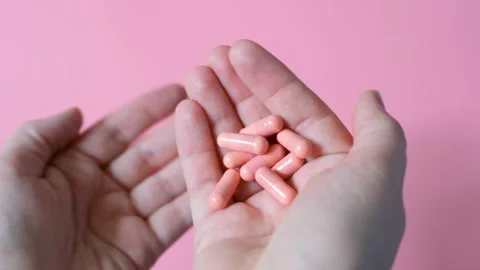 Female hands holding capsules close-up on a pink background. Stock Footage 338372702
