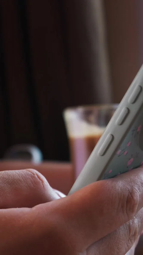 Female Hands Holding Floral Patterned Smartphone in Cozy Cafe Setting Stock Footage 339190816