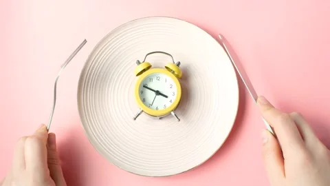 Female hands holding a fork and and knife next to an empty plate on pink Stock Footage 236513708