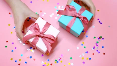 Female hands holding gift boxes on pink background, top view Stock Footage 221456926
