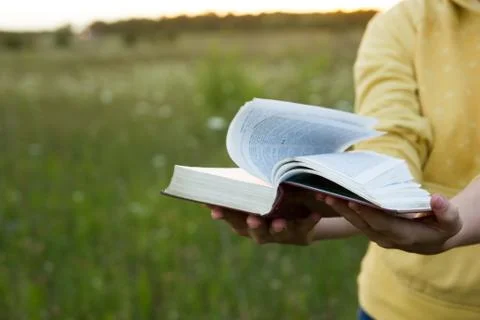 Female hands holding opened hardback book, diary with fanned pag Stock-Fotos