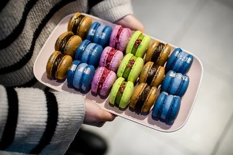 Female hands holding a rectangular plate with colorful macaroons Foto stock