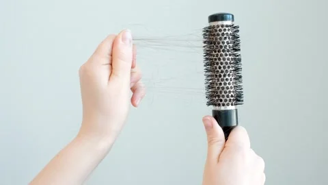 Female hands holding round comb with fallen hair on a gray background close-up. Stock Footage 303462955