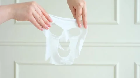 Female hands holding sheet moisturizing mask close-up on white wall background. Stock Footage 281705525