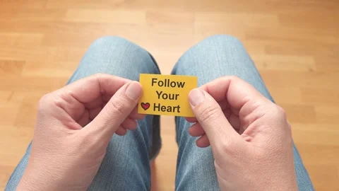 A female hands holding a small yellow card with the phrase Follow Your Heart. Stock Footage 340226573