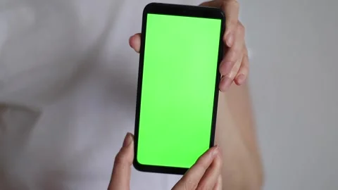 Female hands holding smartphone with green screen on white background. Close up Stock Footage 269463589