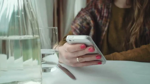 Female hands holding a smartphone at the table. Видео 56874853