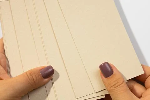 Female hands holding stack of gray-brown cardboard rectangular blank tags for 스톡 사진