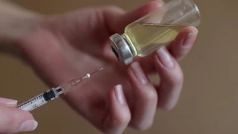 Female hands inject the solution into a vial of vaccine with a syringe Stock Footage 130193518