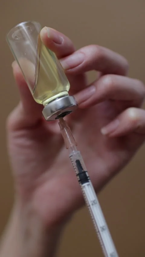 Female hands inject the solution into a vial of vaccine with a syringe.  Stock Footage 271645440
