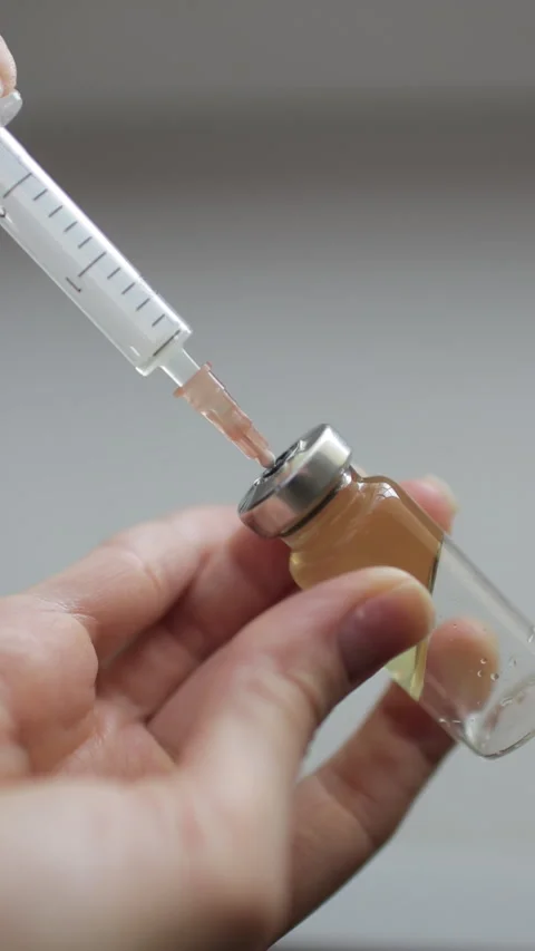 Female hands inject the solution into a vial of vaccine with a syringe.  Stock Footage 272587907