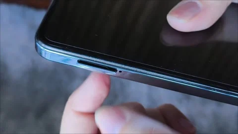 Female hands insert a nano SIM card into the smartphone tray. 库存影片 313355690