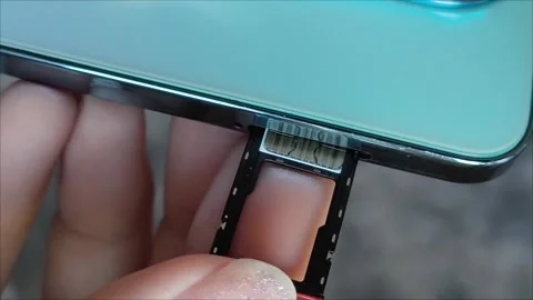 Female hands insert a nano SIM card into the smartphone tray. Stock Footage 313355732