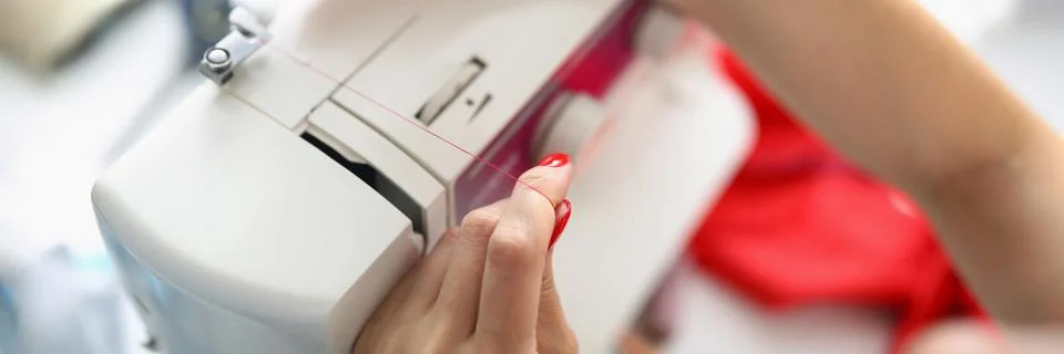 Female hands insert thread into sewing machine Stock Photos