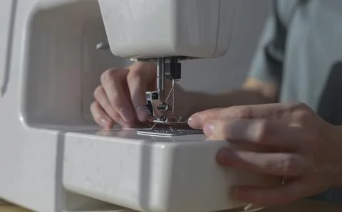 Female hands inserting thread through needle hole in sewing machine, close up Foto stock