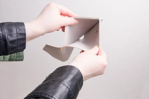 Female hands in a jacket open an empty wallet, white background, bankruptcy c Stock Photos