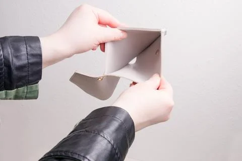 Female hands in a jacket open an empty wallet, white background, bankruptcy c Stock Photos