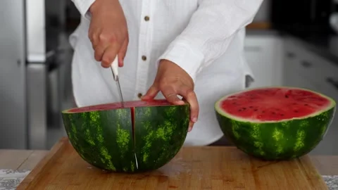 Female hands in the kitchen cut a large ripe watermelon with sharp knife Stock Footage 290983332