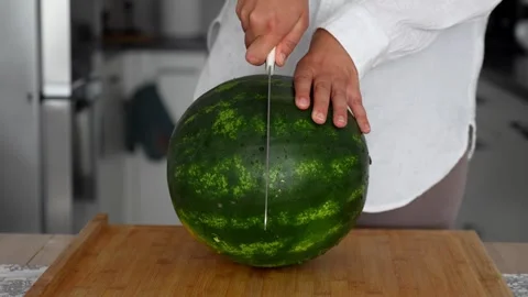 Female hands in the kitchen cut a large ripe watermelon Stock Footage 290983416